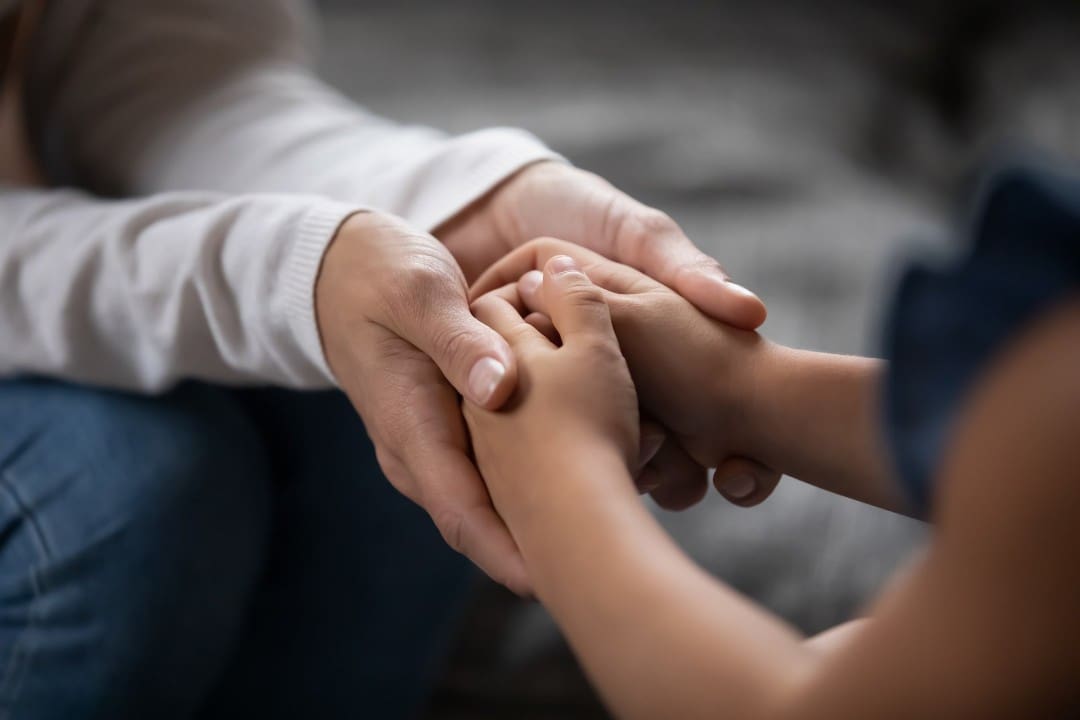 Parent comforting young child through handholding