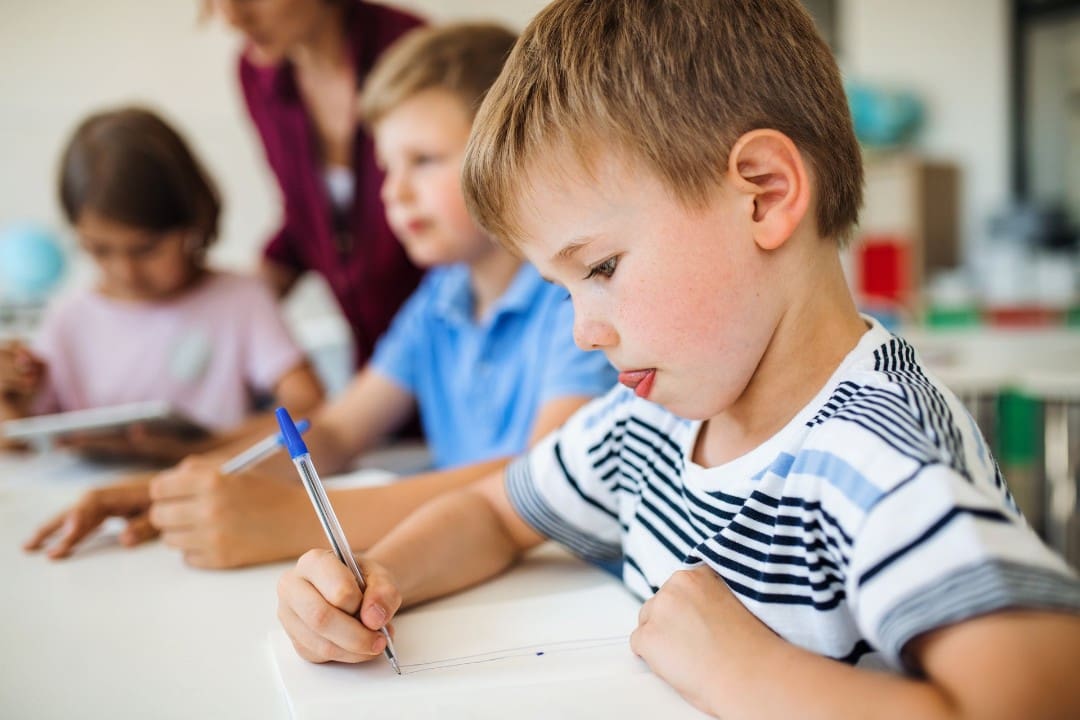 Boy learning to write in preschool classroom