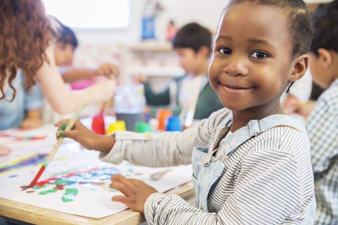 Child in preschool painting with paintbrushes