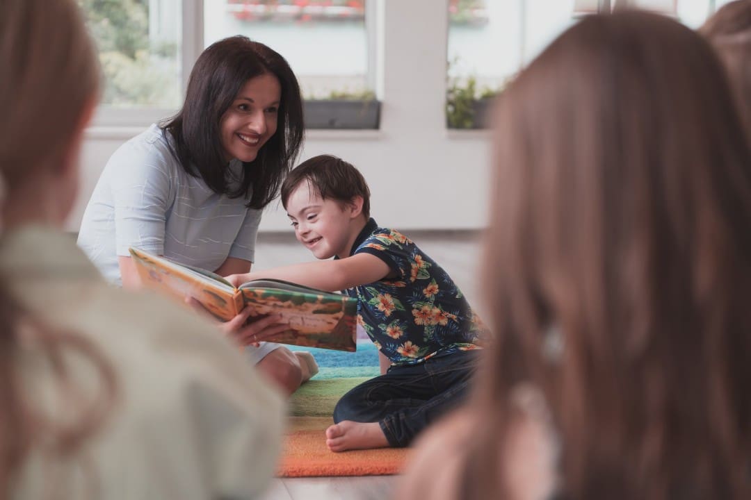 Child care teacher reading book to group of students with disabilities